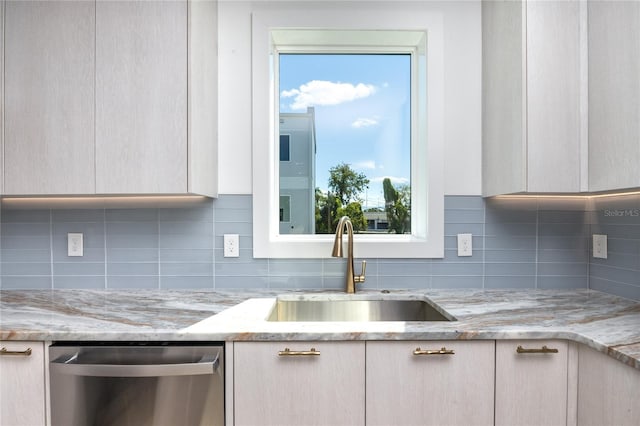 kitchen with light stone countertops, dishwasher, plenty of natural light, and sink