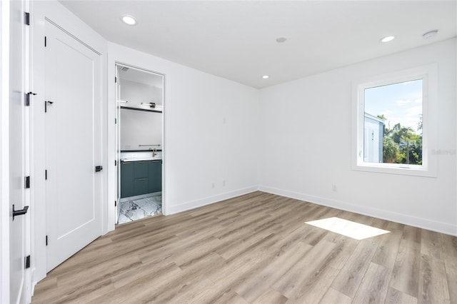 unfurnished bedroom featuring light wood-type flooring and connected bathroom