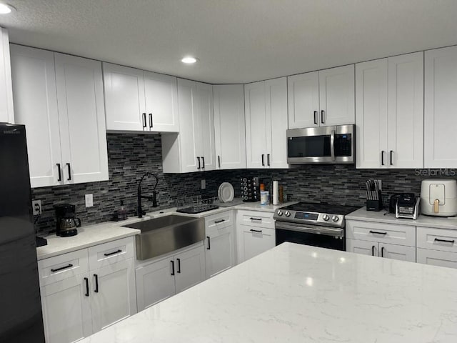 kitchen with white cabinets, sink, appliances with stainless steel finishes, and tasteful backsplash