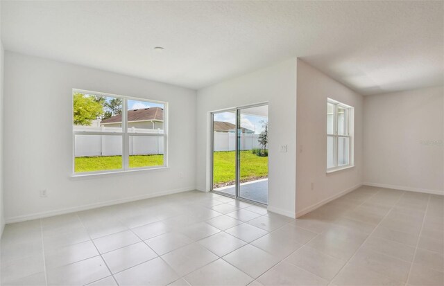 empty room with a healthy amount of sunlight and light tile patterned floors