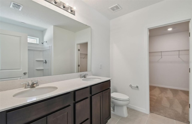 bathroom with toilet, a shower, double sink vanity, and tile patterned flooring