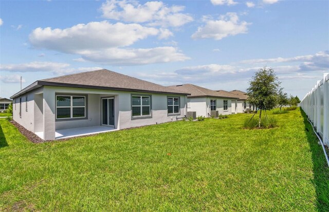 rear view of house featuring central air condition unit, a patio area, and a yard