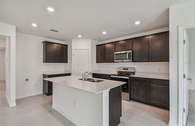 kitchen with sink, dark brown cabinets, a kitchen island with sink, and stainless steel appliances