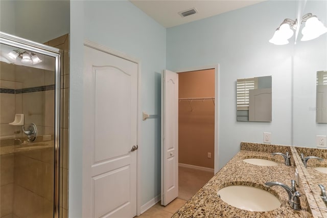 bathroom featuring tile flooring, an inviting chandelier, a shower with door, and double sink vanity