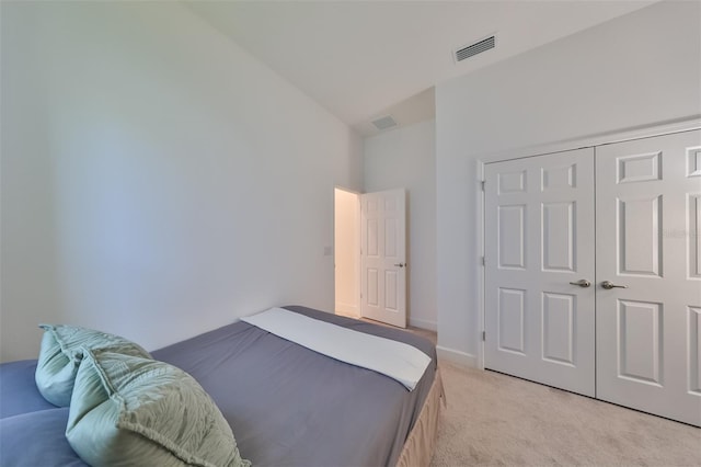 bedroom featuring a closet, high vaulted ceiling, and light colored carpet