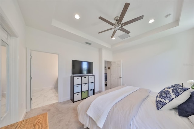 carpeted bedroom with ceiling fan and a tray ceiling