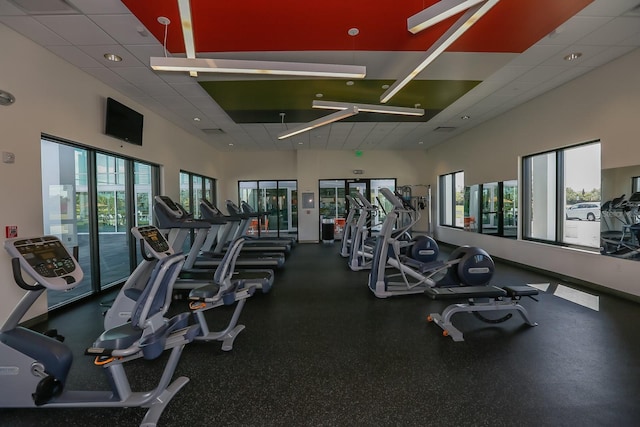 gym with a drop ceiling and a healthy amount of sunlight