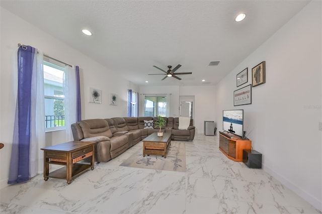 living room with ceiling fan, plenty of natural light, and a textured ceiling