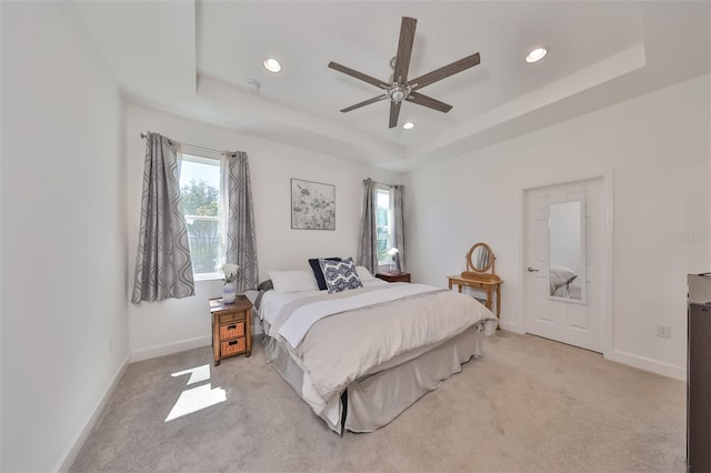 carpeted bedroom featuring ceiling fan and a tray ceiling