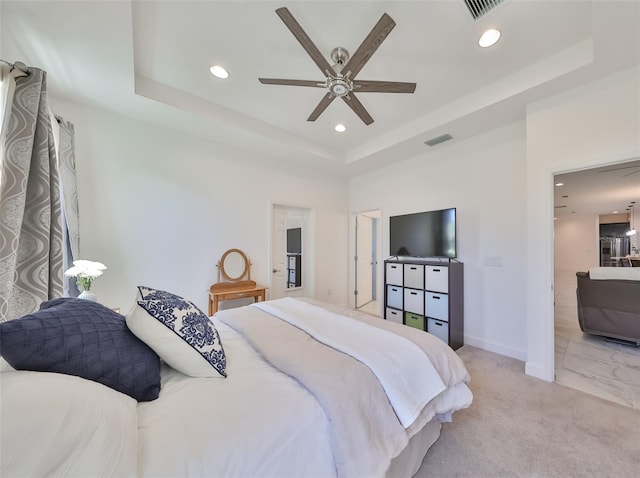 bedroom with light carpet, ceiling fan, and a raised ceiling