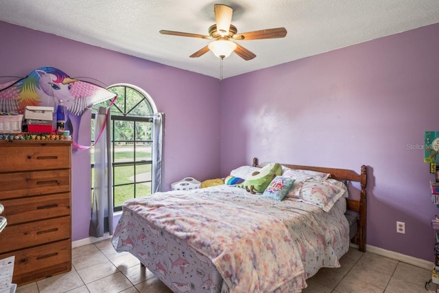 bedroom with ceiling fan, light tile patterned floors, and a textured ceiling