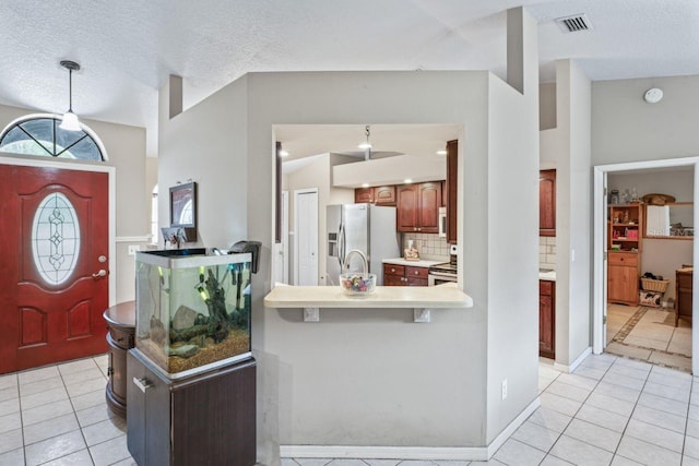 entrance foyer featuring lofted ceiling, light tile patterned flooring, and a textured ceiling