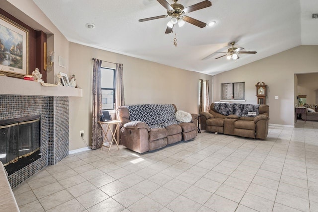 tiled living room with a tile fireplace, ceiling fan, and lofted ceiling