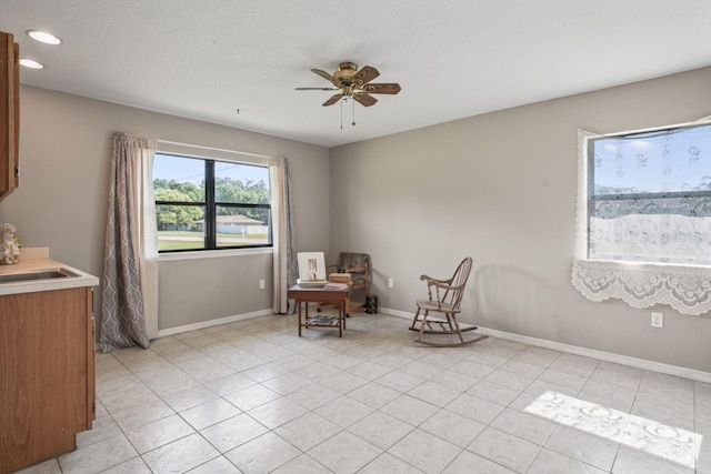 living area with ceiling fan, light tile patterned flooring, and sink