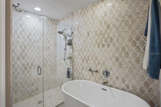 bathroom featuring tile walls, a textured ceiling, and shower with separate bathtub