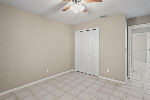 unfurnished bedroom with ceiling fan, a closet, light tile patterned floors, and a textured ceiling