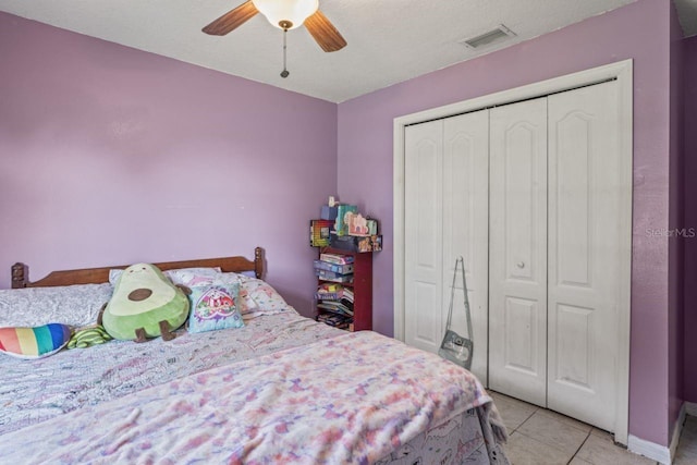 tiled bedroom with ceiling fan, a closet, and a textured ceiling