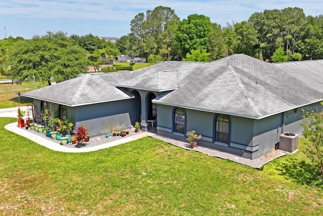 back of property with central air condition unit and a lawn