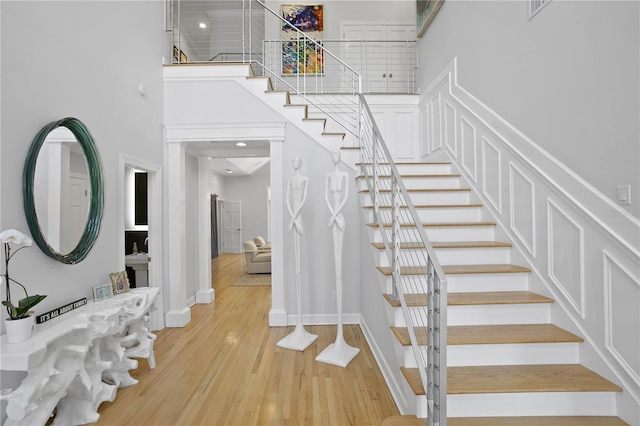 stairs featuring light hardwood / wood-style flooring and a high ceiling