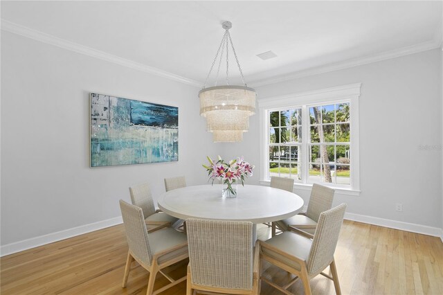 dining area featuring ornamental molding, light hardwood / wood-style floors, and a notable chandelier