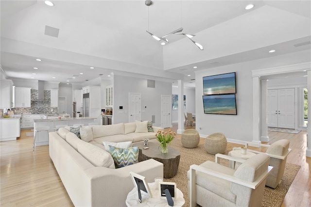 living room featuring high vaulted ceiling, sink, and light wood-type flooring