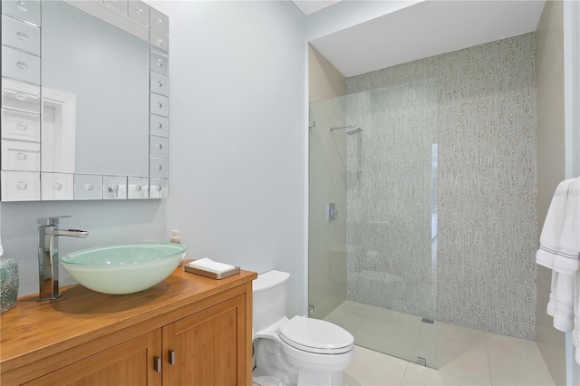 bathroom featuring toilet, tile floors, vanity, and a tile shower