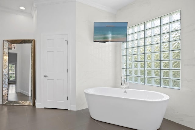 bathroom featuring a bathing tub, crown molding, and tile flooring