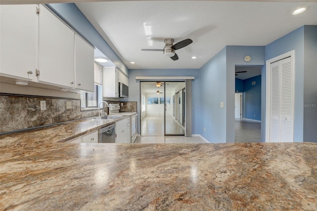 kitchen with ceiling fan, sink, decorative backsplash, white cabinets, and appliances with stainless steel finishes