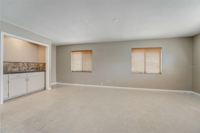 empty room with plenty of natural light, light tile patterned flooring, and sink