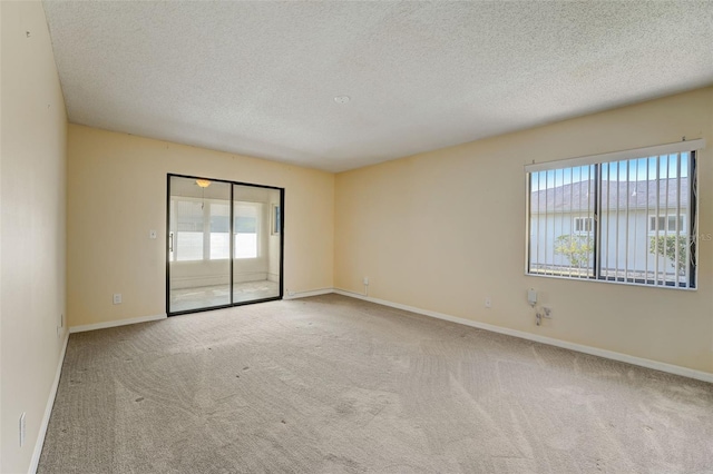 spare room featuring light carpet and a textured ceiling