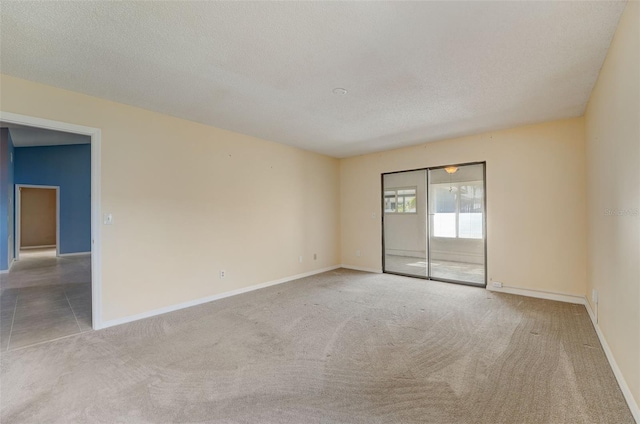 empty room with a textured ceiling and light carpet