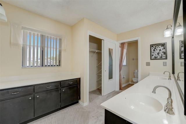 bathroom with vanity, toilet, and a textured ceiling