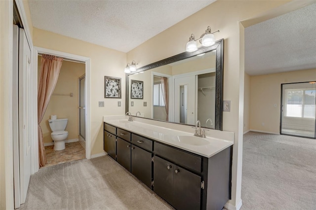 bathroom with vanity, a textured ceiling, toilet, and an enclosed shower