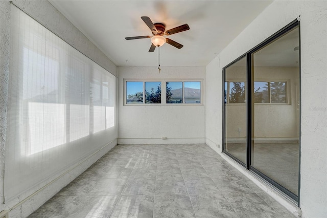 unfurnished sunroom featuring ceiling fan