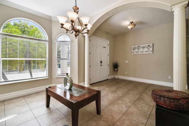 entryway with ornamental molding, an inviting chandelier, light tile floors, and decorative columns