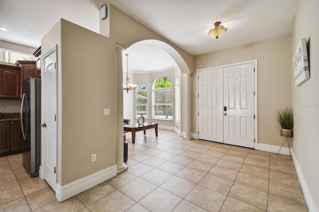 tiled foyer with an inviting chandelier and ornamental molding