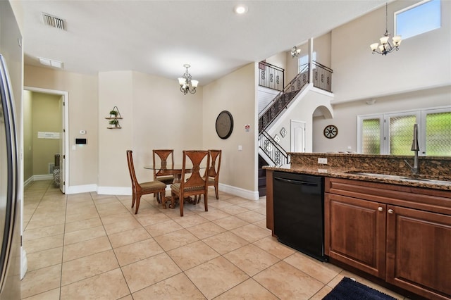 kitchen featuring sink, dishwasher, a notable chandelier, dark stone counters, and decorative light fixtures