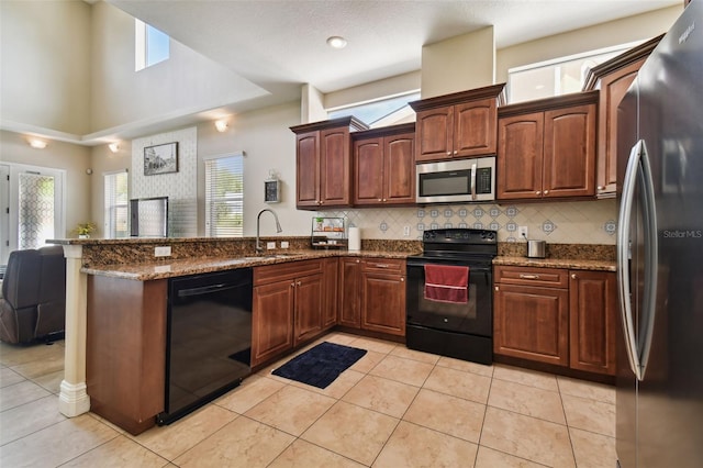 kitchen featuring dark stone countertops, sink, light tile floors, and black appliances