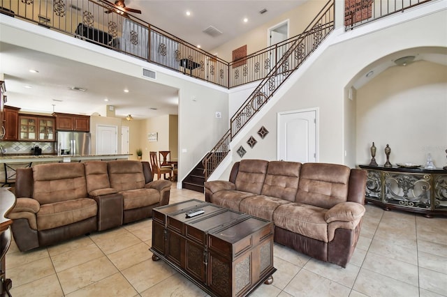 tiled living room with ceiling fan and a towering ceiling