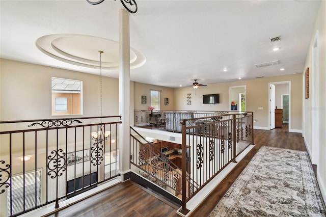 corridor with a tray ceiling and dark hardwood / wood-style floors