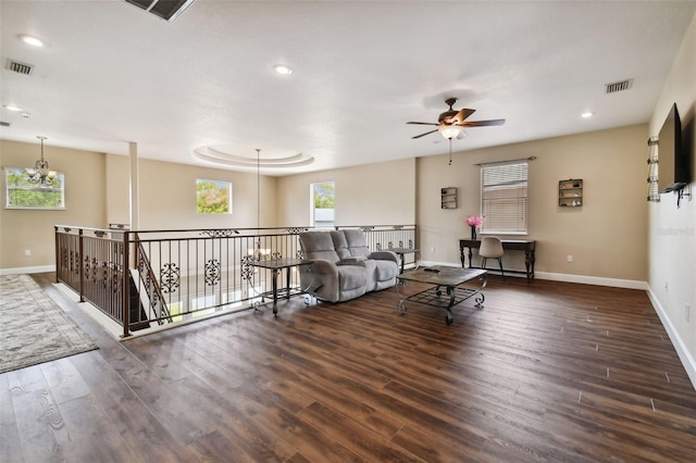 living room with ceiling fan with notable chandelier and dark hardwood / wood-style floors