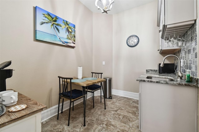 dining area featuring sink, an inviting chandelier, and light tile floors