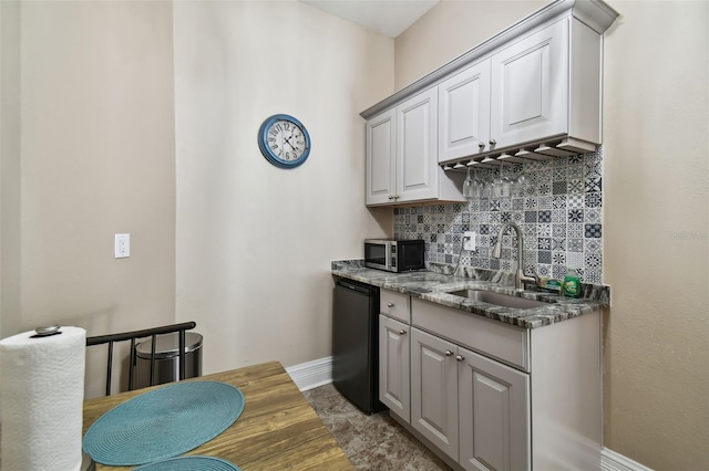 kitchen featuring stone countertops, dishwasher, tasteful backsplash, dark tile flooring, and sink