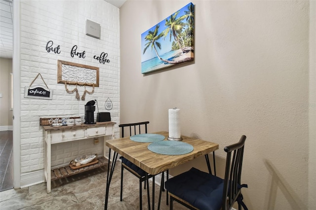 dining space with brick wall and dark tile floors