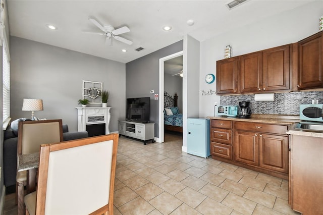 kitchen featuring light tile flooring, ceiling fan, tasteful backsplash, and sink