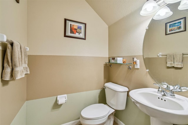 bathroom featuring sink, toilet, and vaulted ceiling