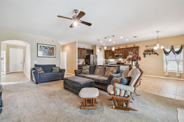 carpeted living room featuring ceiling fan with notable chandelier