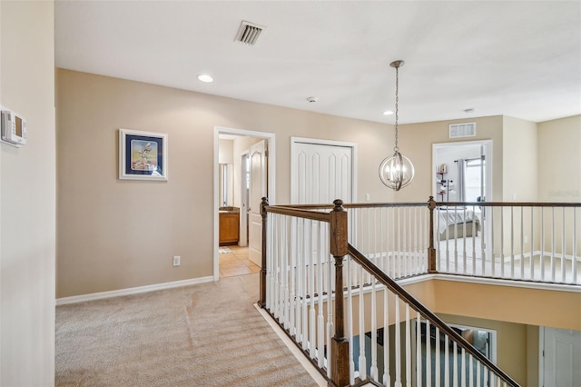 corridor featuring light colored carpet and a chandelier