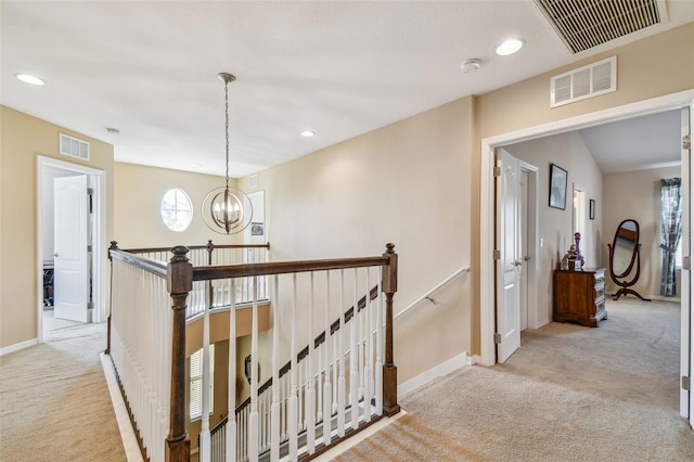 hallway featuring an inviting chandelier and light colored carpet