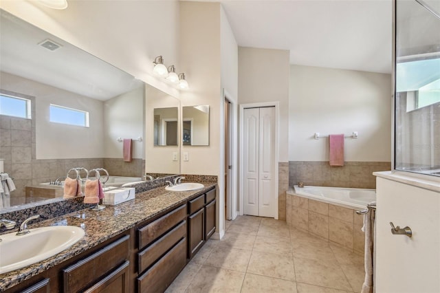 bathroom with double sink vanity, tile flooring, and tiled tub